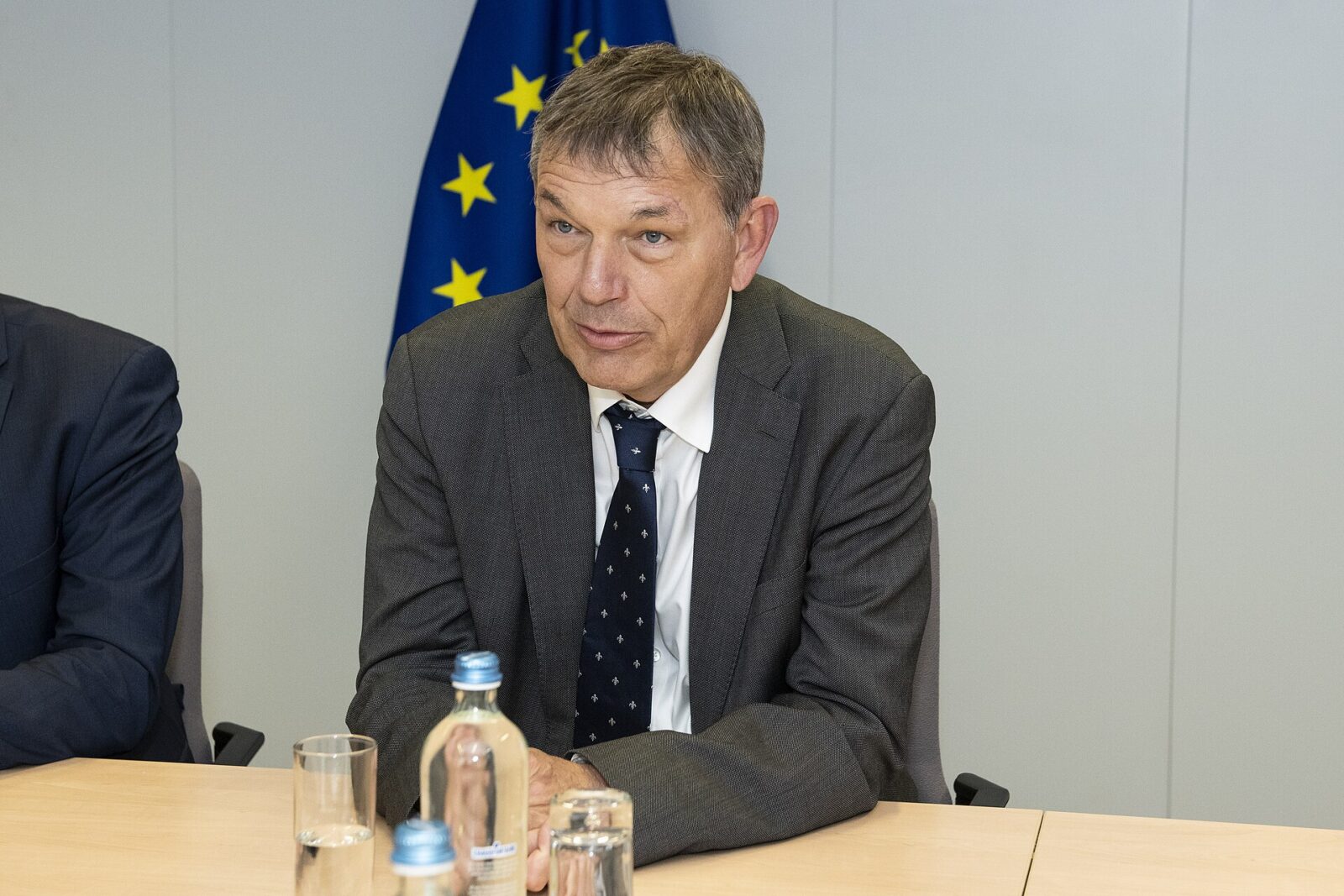 Philippe Lazzarini in a dark suit and tie, standing indoors and facing the camera