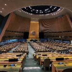 Interior view of the United Nations General Assembly hall with rows of seats and delegate desks
